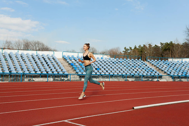 Young woman running during sunny morning on running track. Healthy lifestyle concept. Weight loss exercising - Photo, Image
