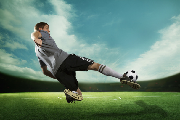 Joueur de football donnant un coup de pied au ballon de football en plein air
 - Photo, image
