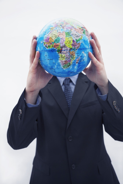 zakenman in een pak een globe voor zijn gezicht te houden - Foto, afbeelding