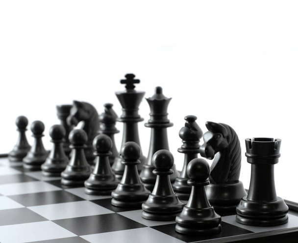 Black chess pieces on the chessboard on white background. Closeup of some chess figures. Copy space - 写真・画像