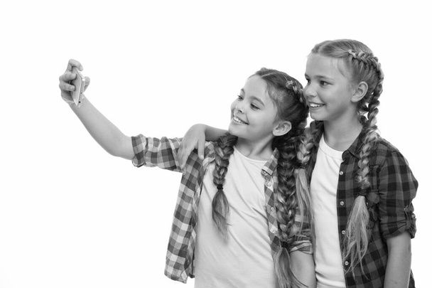 Girls cute small children smiling to phone screen. They like taking selfie for social networks. Problem of young generation. Mobile phone dependence. Mobile phone and internet addiction or obsession - Fotoğraf, Görsel