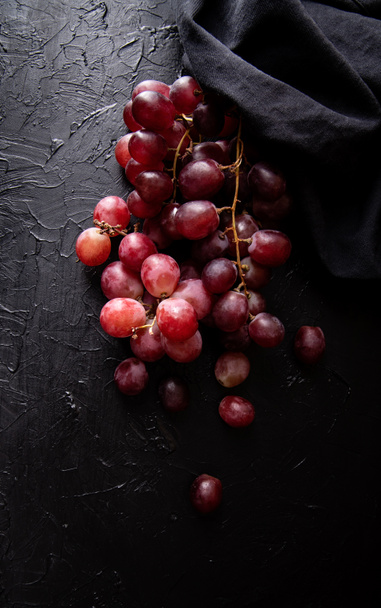 A bunch of red grapes top view on dark background. Dark mood - Photo, Image