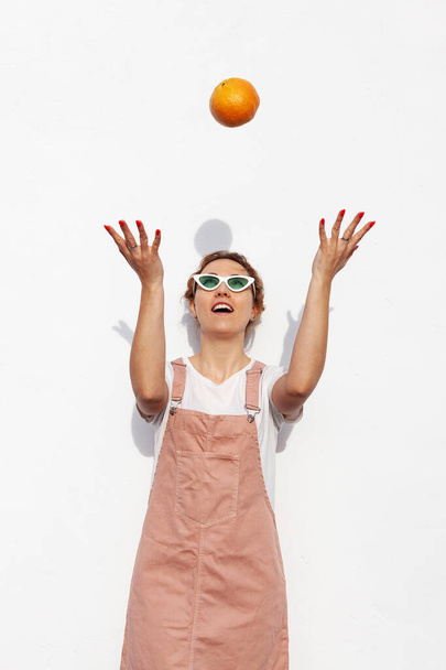 Retrato del estudio de la chica feliz, sonriendo alegremente, lanzando un pomelo, de pie aislado sobre fondo blanco. Frutas tropicales sabrosas, alimentos saludables, dieta de alimentos crudos
 - Foto, imagen