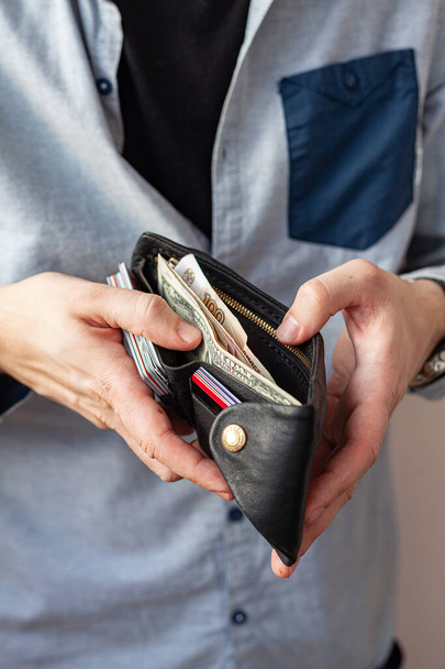male hands hold a purse. A wallet with little money in it. The concept of poverty and bankruptcy - Φωτογραφία, εικόνα