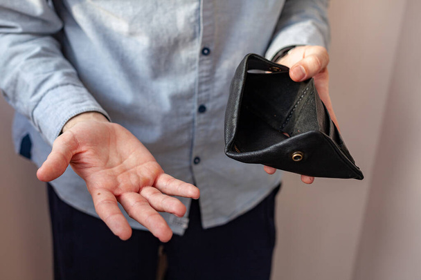 Erkek eli boş bir çanta ve bozuk para tutuyor. İçinde az para olan bir cüzdan. Yoksulluk ve iflas kavramı - Fotoğraf, Görsel