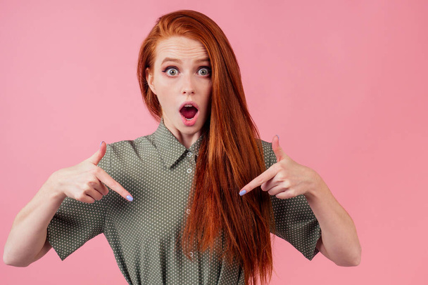 redhair ginger woman amazed and surprised in cotton green white peas dress in pick background studio - Photo, image