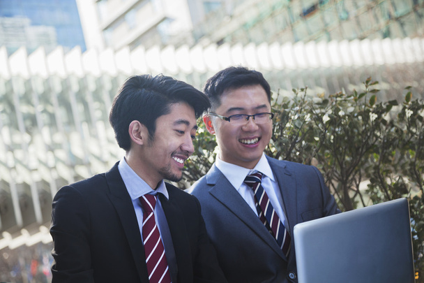 Geschäftsleute schauen gemeinsam im Freien auf Laptop - Foto, Bild