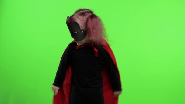 Vicces kislány jelmezben és maszkban szuperhőst játszik. Nemzeti szuperhős nap - Felvétel, videó