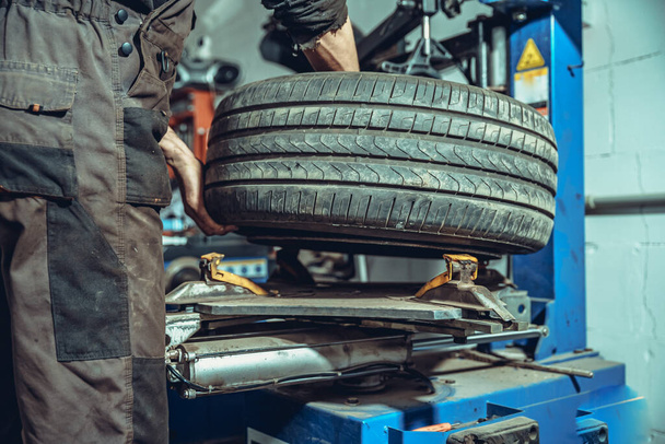 Un tecnico cambia gomme su una ruota di un'auto su una macchina speciale in un servizio di pneumatici
 - Foto, immagini