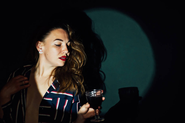 girl on green background with a glass of red drink wine smoke looks aside - Zdjęcie, obraz