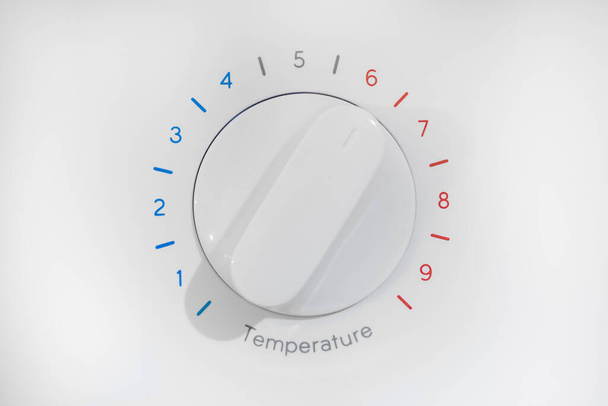 Termostat z dziewięcioma poziomami regulacji temperatury, niebieską strefą zimna i czerwoną gorącą, białą tarczą na 6 pozycji, izolowany na białym tle. - Zdjęcie, obraz