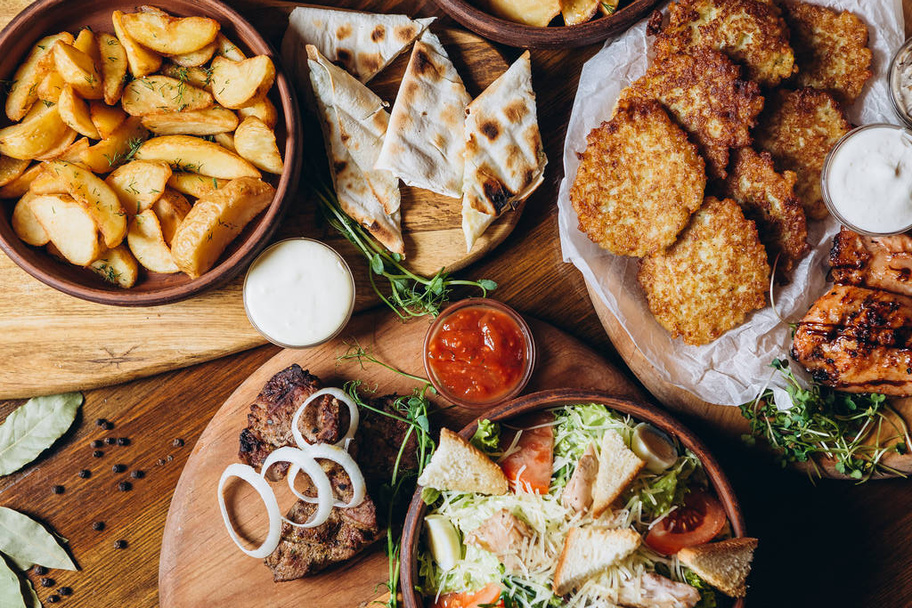 large and generously covered with delicious dishes table on which there are various dishes of Ukrainian cuisine: barbecue, fried potatoes, salad, sauce, pita bread with cheese - Zdjęcie, obraz
