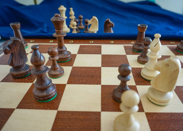 A chess game in middlegame or endgame with wooden pieces taking different positions on the wooden chessboard - Photo, Image