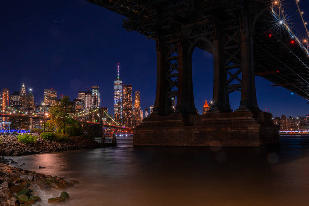 Панорамный вид на Манхэттенский мост в Нью-Йорке ночью с видом на Манхэттен через реку Гудзон
. - Фото, изображение