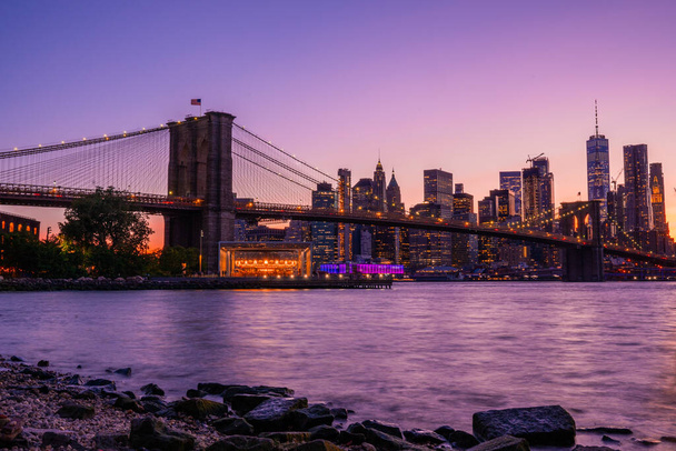 Mágica noche púrpura puesta de sol vista del puente de Brooklyn desde el parque de Brooklyn con una vista inferior de Manhattan en el otro lado del río Hudson
. - Foto, Imagen