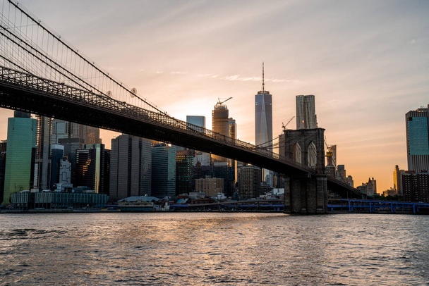 Magical evening sunset view of the Brooklyn bridge from the Brooklyn park with a lower Manhattan view on the other side of the Hudson river. - Φωτογραφία, εικόνα