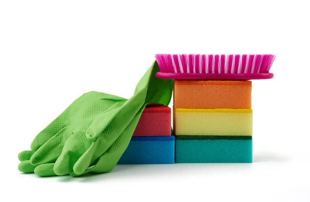 Ev temizliği için eşyalar: yeşil lastik eldivenler, fırça, beyaz arka planda toz almak için çok renkli süngerler - Fotoğraf, Görsel