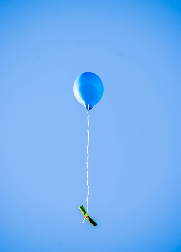 színes léggömbök repülnek a kék égen a béke és a barátság üzenetével, amit a gyerekek írtak. - Fotó, kép