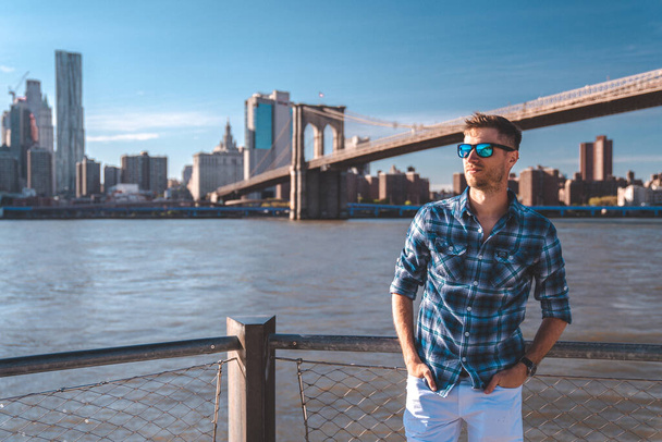 Junger Mann am Hudson River mit einer Brücke in Brooklyn im Hintergrund. - Foto, Bild
