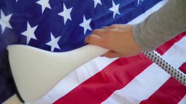 Kobieta głaszcze flagę USA żelazkiem parowym. Przygotowania do Dnia Niepodległości USA - Materiał filmowy, wideo