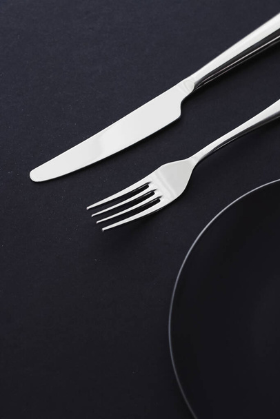 Puste talerze i srebra na czarnym tle, premium zastawy stołowe na świąteczną kolację, minimalistyczny design i dieta - Zdjęcie, obraz