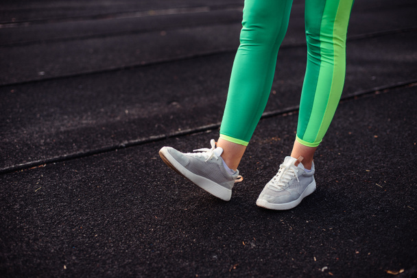Gambe di una ragazza in leggings verde chiaro in una sessione di allenamento su uno stadio, per strada
 - Foto, immagini