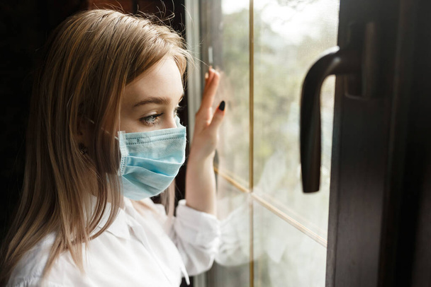 COVID-19 Pandemic Coronavirus Woman home isolation quarantine wearing face mask protective for spreading of disease virus SARS-CoV-2. Girl isolation mask on face against Coronavirus Disease 2020. - 写真・画像