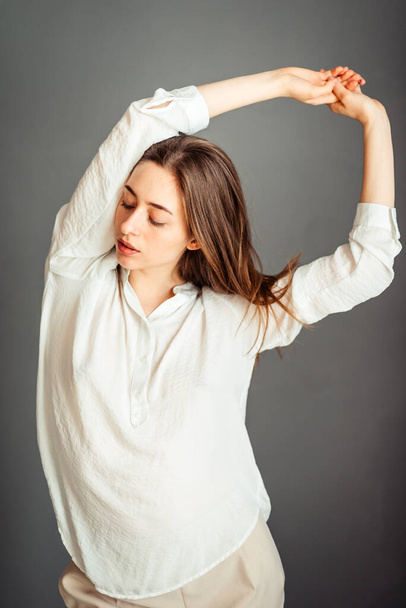 Young girl in a white shirt on a gray background. French woman in white blouse against a background of gray walls. Without retouching. - Foto, Imagem