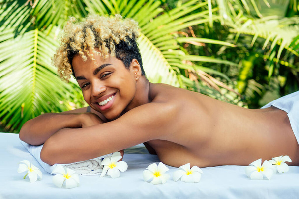 attractive african american female get treatment massage in tropics resort outdoor salon - Foto, afbeelding