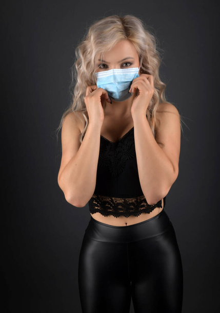 Beautiful blonde woman with long curly hair with respirator mask - Photo, Image