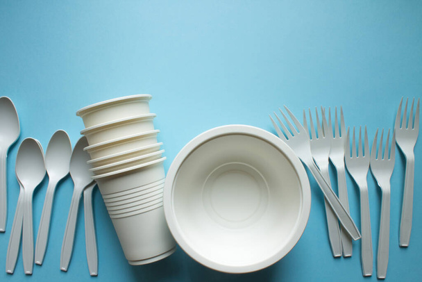 Biodegradable disposable tableware: plates, glasses and spoons with forks on a blue background close-up copy space. Trend: ecology. - Photo, Image