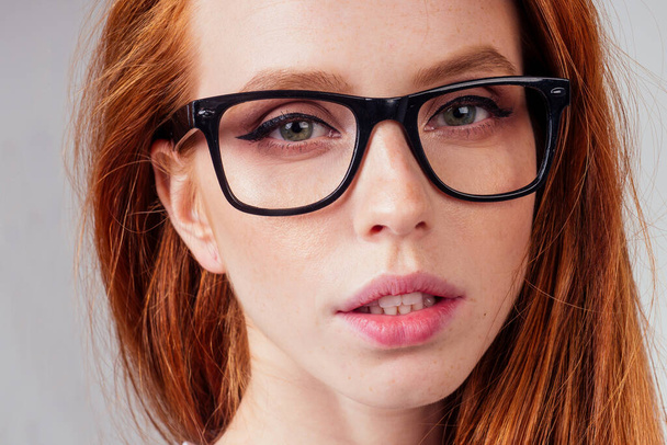 redhaired ginger woman wearing glasses and white cotton eco t-shirt in gray studio background - Foto, Bild
