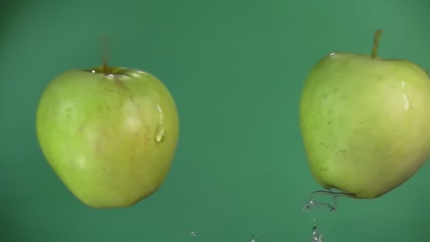 Kaksi vihreää omenaa lentää ja nostaa vesipisaroita hidastettuna
 - Materiaali, video