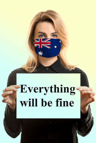 Κορίτσι με ξανθά μαλλιά σε μια μάσκα με τη σημαία της Αυστραλίας και ένα φύλλο με την επιγραφή "Τα πάντα θα είναι μια χαρά". - Φωτογραφία, εικόνα