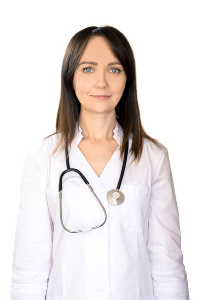 Fiatal nő orvos sötét hajú, fehér orvosi kabátban, sztetoszkóppal, mosolygós. - Fotó, kép