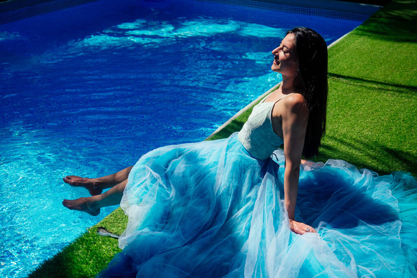 indian woman posing in blue long dress near swimming pool - Foto, Imagem