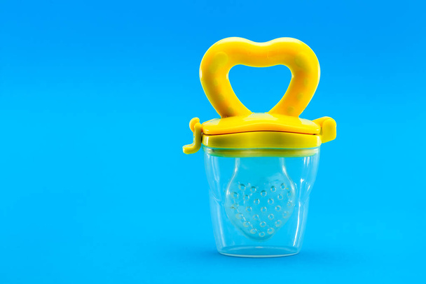 Fruit feeder for feeding weaned babies isolated on a blue background with a copy space, nobody. - Foto, afbeelding