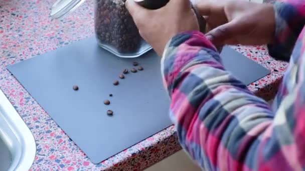 Henkilö jauhaa käsin orgaanisia paahdettuja kahvipapuja kotona
 - Materiaali, video