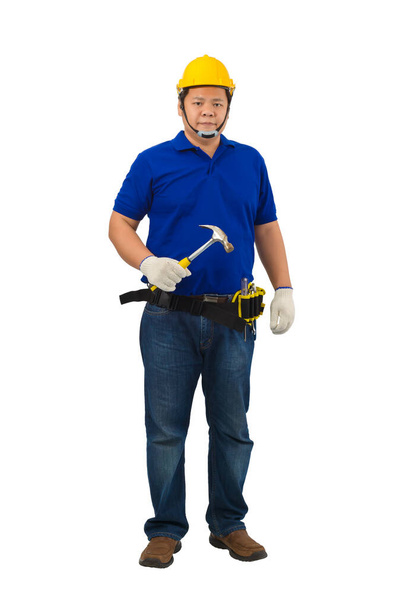 Bauarbeiter in blauem Hemd mit Schutzhandschuhen, Helm mit Werkzeuggürtel in der Hand, Hammer isoliert auf weißem Hintergrund mit Schneideweg - Foto, Bild