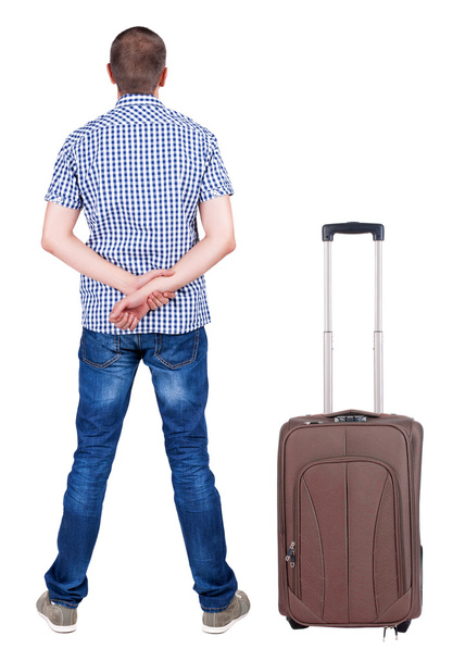 Back view of young man traveling with suitcase. - Foto, afbeelding