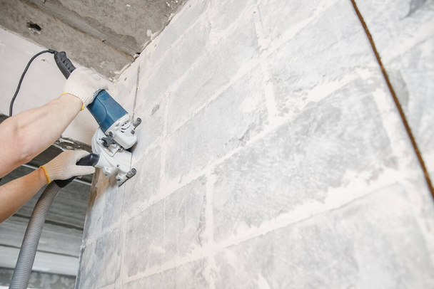 İnşaat işçisi beton duvardaki elektrikli kovalamacayı kesiyor. - Fotoğraf, Görsel