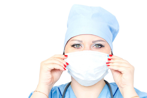 Close-up of a female doctor putting on a medical mask while looking at the camera. - Foto, afbeelding