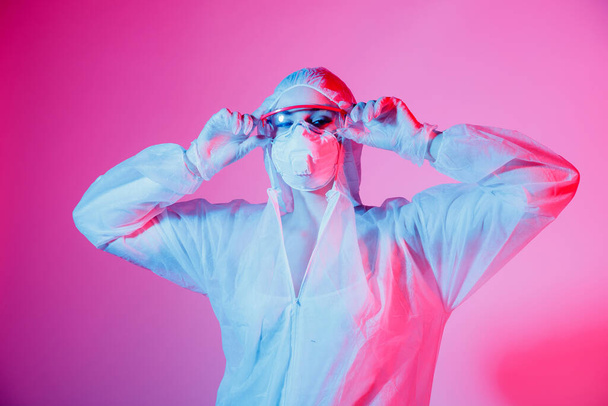 Koronawirus kobieta chodzenie z maską chirurgiczną ochrona twarzy różowy i niebieski tło - Zdjęcie, obraz