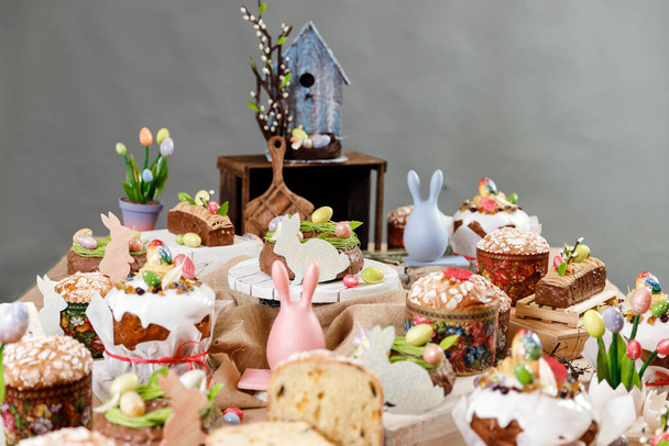 Пасхальный торт ортодоксальный сладкий хлеб кулич и разноцветные шоколадные яйца на праздничном столе - Фото, изображение