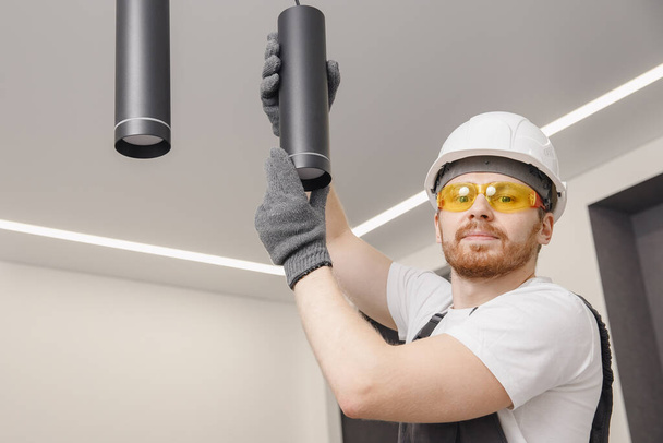 Eletricista está reparando luminárias para lâmpada e spot loft estilo no teto
 - Foto, Imagem