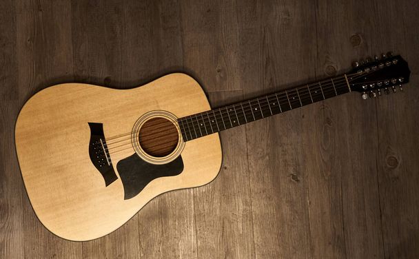 Guitarra acústica completa de 12 cuerdas en un suelo de madera marrón
 - Foto, Imagen
