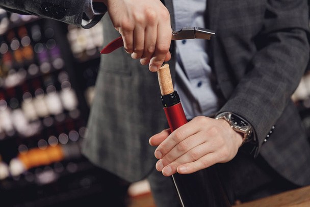 Opening wine bottle with corks crew on dark background restaurant - Фото, изображение