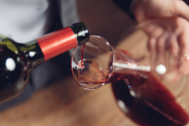 Sommelier man giet rode wijn in decanter voor beluchting van smaak en aroma - Foto, afbeelding