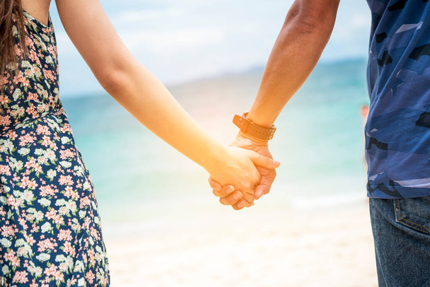Para kochanków trzyma się za ręce na tropikalnej letniej plaży. Skup się na dłoniach z aktywnością szczęścia. Romantyczna miłość podróżuje razem. Koncepcja stylu życia miłośnika wakacji. - Zdjęcie, obraz