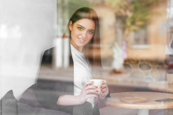 Young charming woman while sitting alone in coffee shop - Foto, Bild